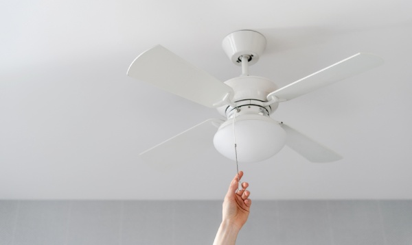 A hand turning on ceiling fan switch