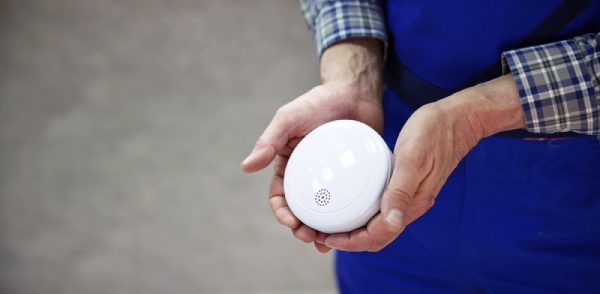 A man holding a smoke alarm detector