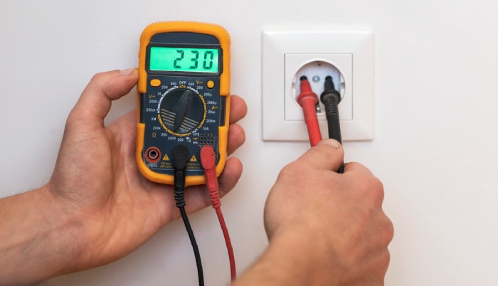 A man measuring voltage in electrical socket