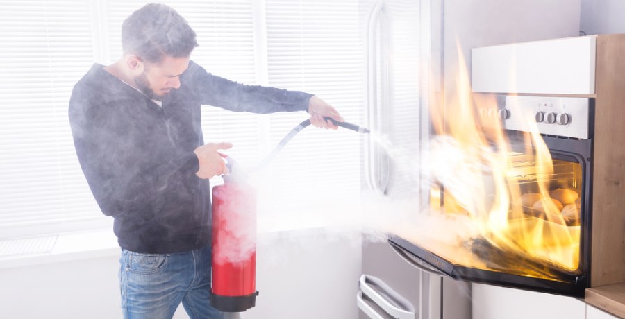 A man using a fire extinguisher to put out a microwave fire