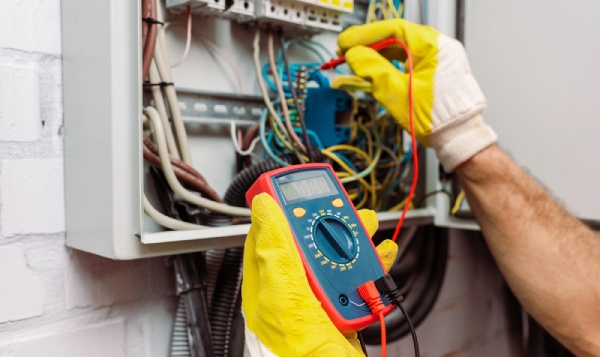 An electrician checking voltage of an electrical panel