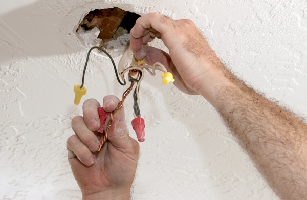 An electrician separating electrical wires in the ceiling