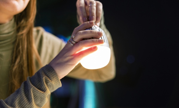 A woman holding a smart light bulb