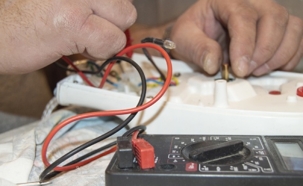 An electrician using a digital voltmeter