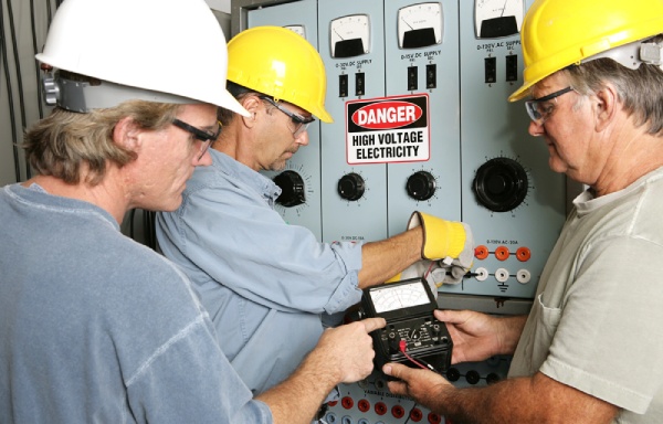 Three electricians working on a high voltage electrical panel