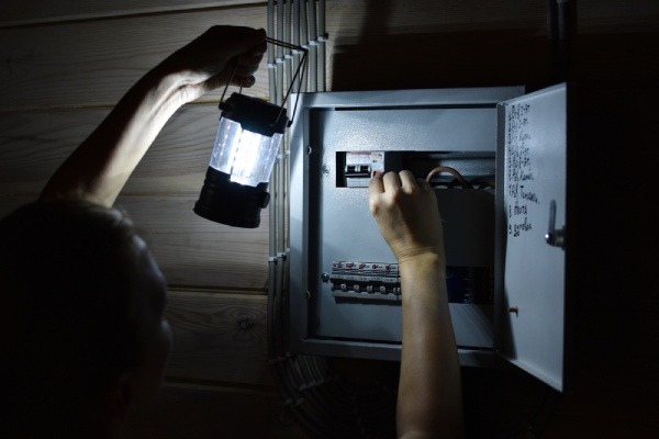 A person switching off electrical power at home